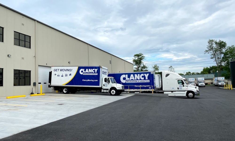 Several Clancy moving trucks parked outside a large warehouse