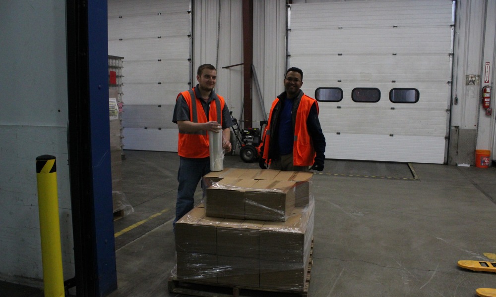 Two warehouse workers wearing high-visibility orange vests